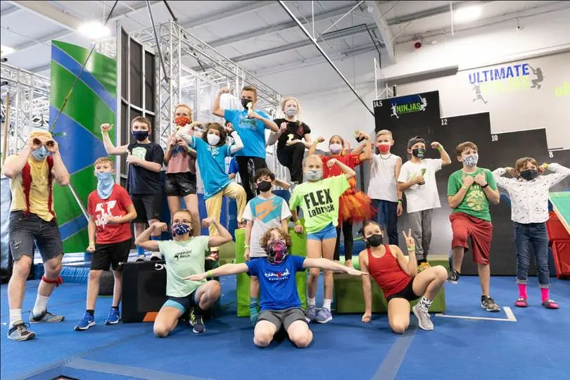 Group of children flexing and posing on mats in a ninja gym.