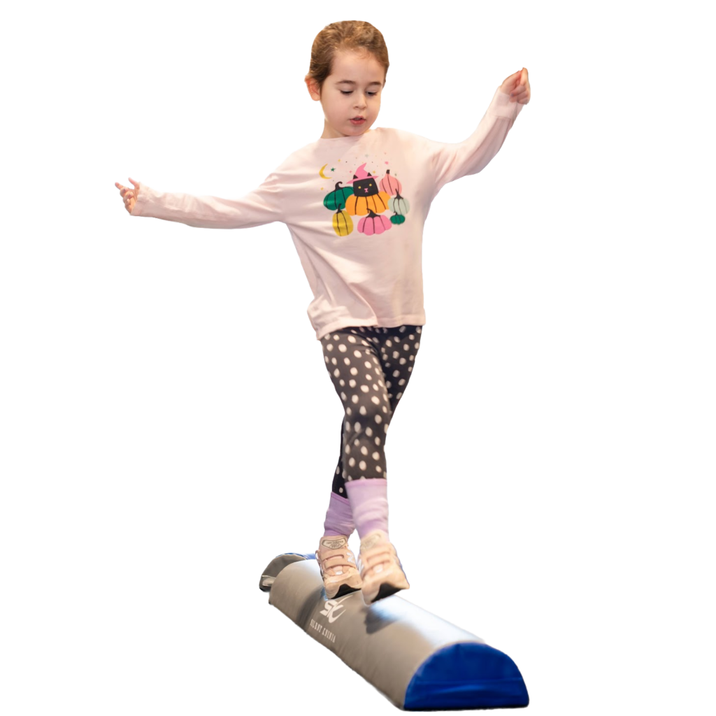 Young girl balancing on a Half Log obstacle with arms outstretched.